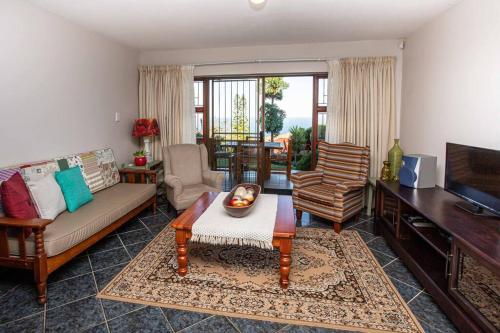 a living room with a couch and a television at 2 Bedroom Holiday Flat in Dana Bay in Mossel Bay