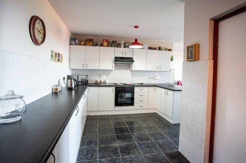 a kitchen with white cabinets and a black counter top at 2 Bedroom Holiday Flat in Dana Bay in Mossel Bay