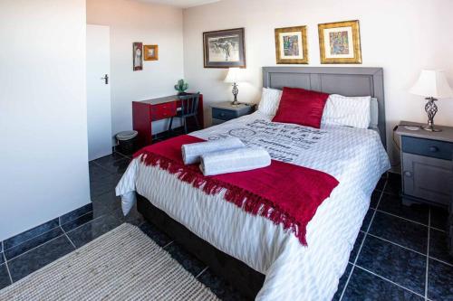 a bedroom with a large bed with red pillows at 2 Bedroom Holiday Flat in Dana Bay in Mossel Bay