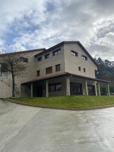 a large white building with a tree in front of it at Hotel & Apartamentos Cons da Garda in San Vicente de O Grove