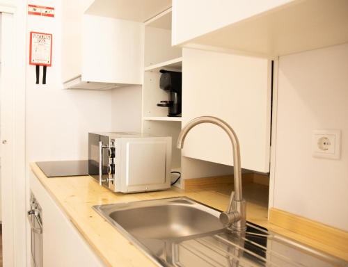 eine Küche mit einer Spüle und einer Mikrowelle in der Unterkunft Apartamentos do Corgo in Vila Real