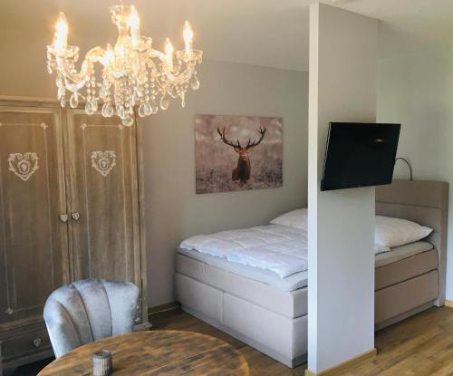 a bedroom with a bed and a table and a chandelier at The Lodge Braunlage in Braunlage
