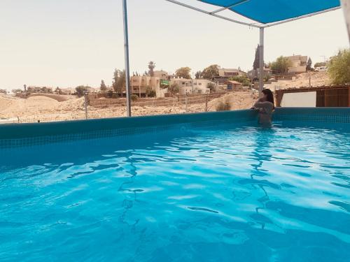 a woman standing in a pool of blue water at Tamar's House in Arad