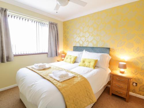 a bedroom with a large white bed with yellow walls at Rhos Deiniol in Porthmadog
