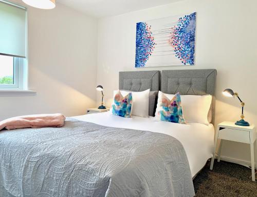 1 dormitorio con 1 cama blanca grande con almohadas en Waverley, en East Kilbride