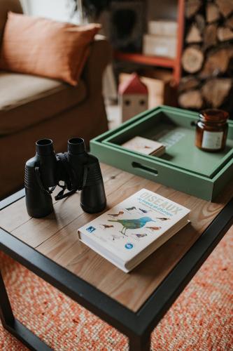 a coffee table with a book and binoculars on it at Gîtes du Bulz, en pleine forêt proche de la mer in Pleyber-Christ