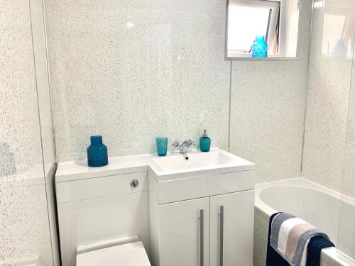 a bathroom with a white sink and a bath tub at Waverley in East Kilbride