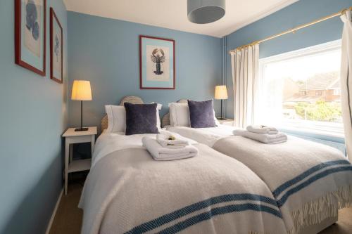 two beds in a bedroom with blue walls and a window at Quay Cottage - Aldeburgh Coastal Cottages in Aldeburgh