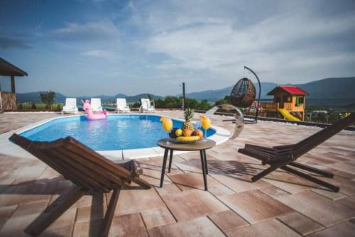 a pool with two chairs and a table with fruit on it at Villa Vanesa Bihać in Bihać
