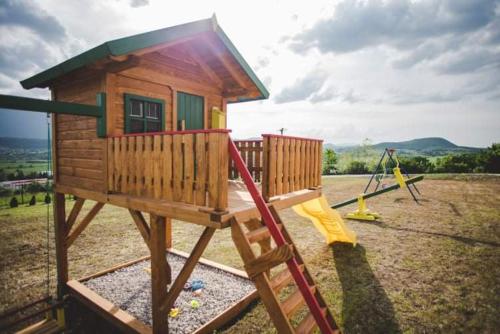 a small wooden house with a slide in a field at Villa Vanesa Bihać in Bihać