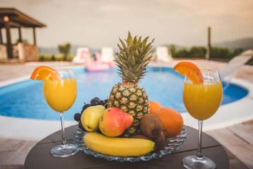 a plate of fruit with two glasses of orange juice at Villa Vanesa Bihać in Bihać