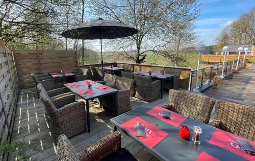 a patio with tables and chairs and an umbrella at Hôtel Restaurant Lamy in Troisvierges