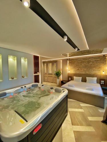 a large bath tub in a room with a bed at Spa Pleasure Apartman in Novi Sad