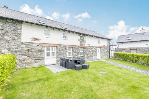 an exterior view of a stone house with a yard at Sgubor in Holyhead