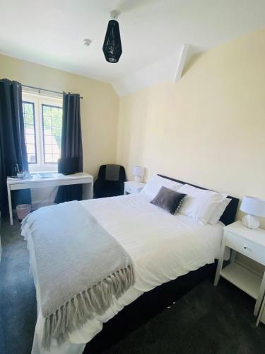 a bedroom with a large white bed and a desk at Mirfield Monastery B&B in Mirfield