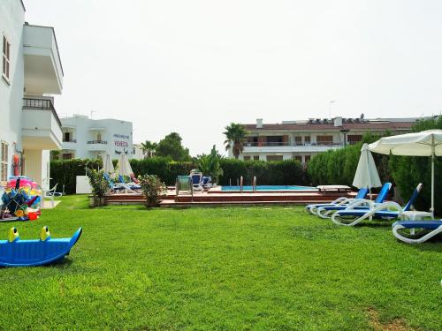 a yard with lounge chairs and a swimming pool at Venecia Apartments in Port d'Alcudia