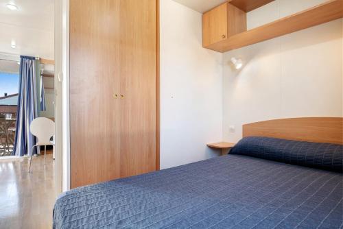 a bedroom with a blue bed and wooden cabinets at Eloy Playa 3 - Sólo Familias in Roche