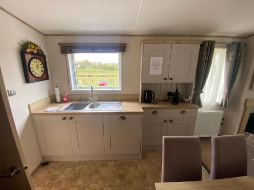 a small kitchen with a sink and a window at Starling Six Berth caravan in Alford