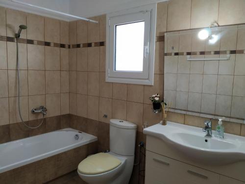 a bathroom with a toilet and a sink and a tub at Villa on the Beach in Periyiálion