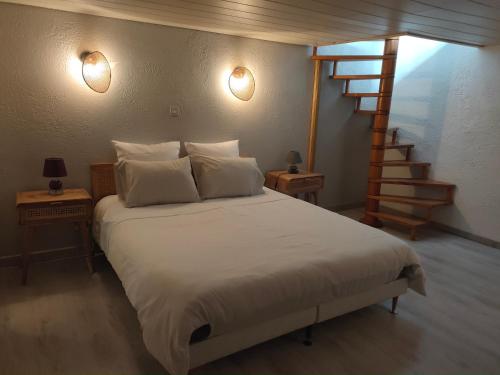 a bedroom with a white bed with a staircase at Gite la Denteliere in Calais
