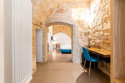a room with a stone wall with a desk and a blue chair at B&B A C-Caste in Monopoli