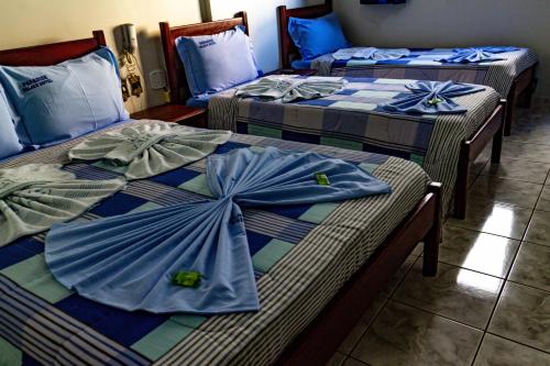 three beds in a room with blue sheets at Paradise Palace Hotel in Aparecida