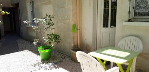 une table et des chaises vertes sur une terrasse avec une plante dans l'établissement Locations IDEALOGIS Studios et T2 avec WIFI LAVERIE VELOS, à Rochefort
