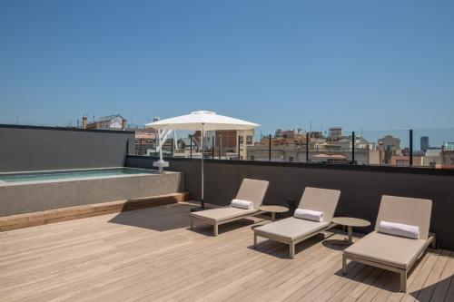 a rooftop patio with chairs and an umbrella on a roof at Room Mate Gerard in Barcelona