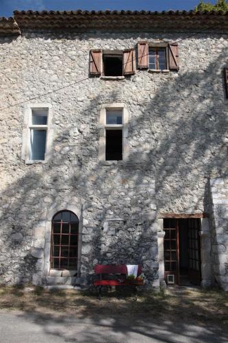 un bâtiment en pierre avec des fenêtres et un banc rouge devant dans l'établissement Le Mas de Mo, au coeur des paysages du Verdon, à Bargème