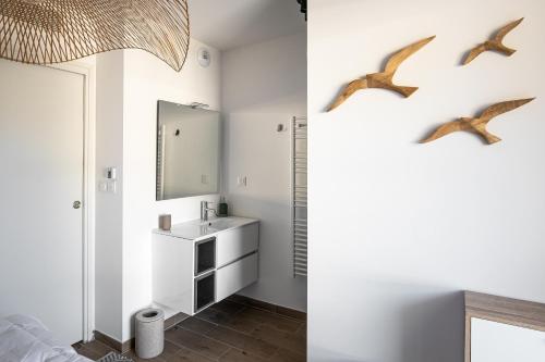 łazienka z umywalką i ptakami na ścianie w obiekcie Superbe appartement bord de mer w mieście Saint-Mandrier-sur-Mer