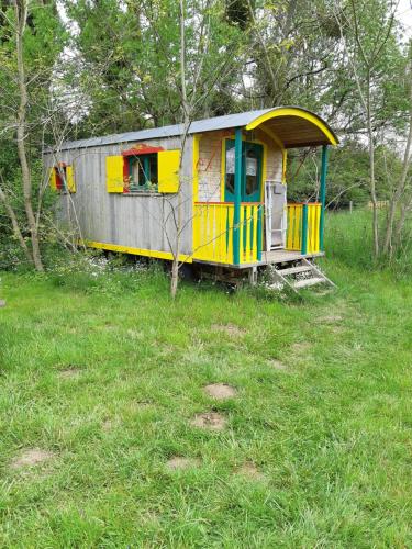 Saint-Augustin的住宿－Roulotte de l'Aubetin，坐在田野里的一辆黄色和蓝色的火车车