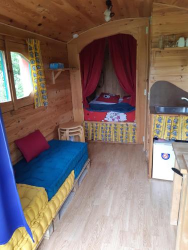 a bedroom with two beds in a wooden house at Roulotte de l'Aubetin in Saint-Augustin