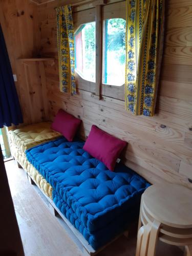 Sofá azul en una habitación con ventana en Roulotte de l'Aubetin, en Saint-Augustin