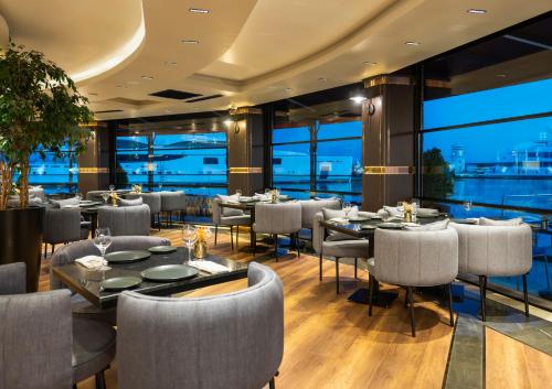 ein Restaurant mit Tischen und Stühlen und großen Fenstern in der Unterkunft Crowne Plaza - Istanbul Tuzla Viaport Marina, an IHG Hotel in Istanbul