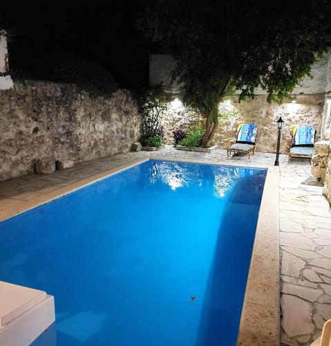 a large blue swimming pool with two blue chairs at Casa del Maestro in Prinés