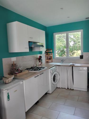 a kitchen with white cabinets and a washer and dryer at Maison studio individuelle fraichement rénovée in Paray-le-Frésil