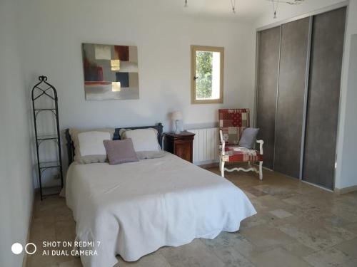 a bedroom with a large bed and a chair at Proche Uzès petit gîte avec grande cuisine d'été et piscine in Saint-Siffret