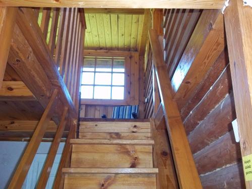 an attic staircase in a log cabin with a window at Pakrasti in Svente