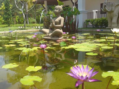 una statua di una donna seduta in uno stagno con ninfee di Villa Chaya a Khao Lak