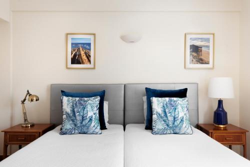 two beds with blue pillows in a bedroom at The Blue Bamboo Hotel - Duna Parque Group in Vila Nova de Milfontes