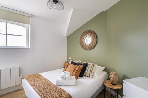 1 dormitorio con cama y espejo en la pared en L'EUCALYPTUS - Charmant appartement de 52m2 en Dinard