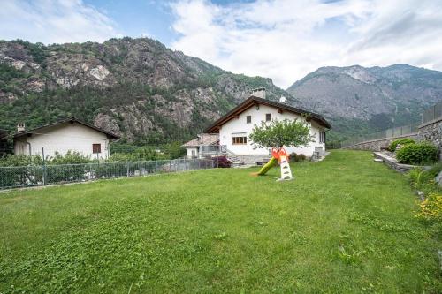 a yard with a house and a tree in the grass at The Green Owl in Antey-Saint-André