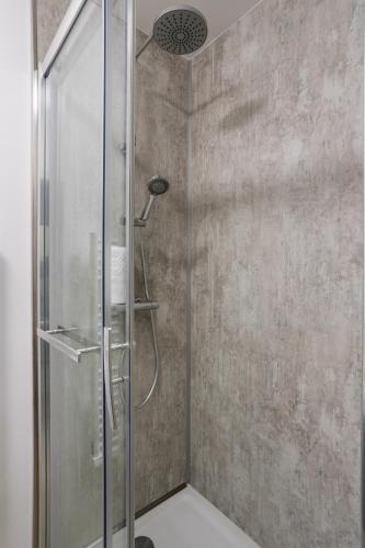 une douche avec une porte vitrée dans une salle de bain dans l'établissement L'EUCALYPTUS - Charmant appartement de 52m2, à Dinard