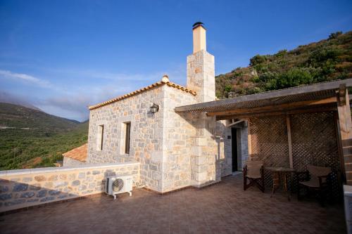 a stone building with a table and chairs on a patio at Traditional Apartments Plagiaki in Neon Oitilon