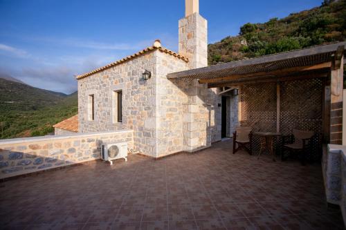 a stone house with a patio with a table at Traditional Apartments Plagiaki in Neon Oitilon