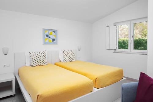 a bedroom with two beds with yellow sheets at Quinta Do Moinho De Vento - Racket & Country Club - Duna Parque Group in Vila Nova de Milfontes