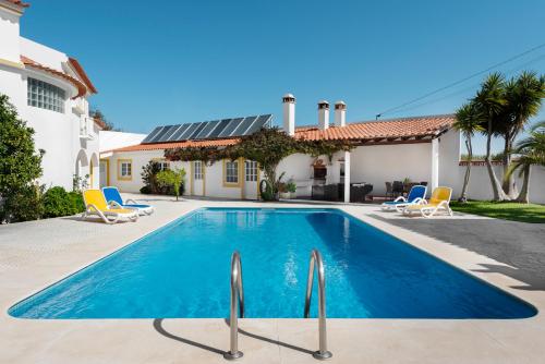 a swimming pool in front of a house at Quinta Do Moinho De Vento - Duna Parque Group in Vila Nova de Milfontes