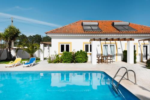 a villa with a swimming pool and a house at Quinta Do Moinho De Vento - Duna Parque Group in Vila Nova de Milfontes