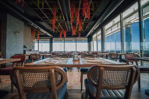 Un comedor con mesas y sillas y ventanas. en Panagia Premier Trabzon, en Trabzon