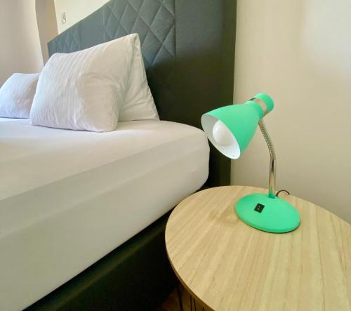 a green lamp on a table next to a bed at Pension Rohrer am Murradweg - Ehrenhausen an der Weinstrasse in Ehrenhausen